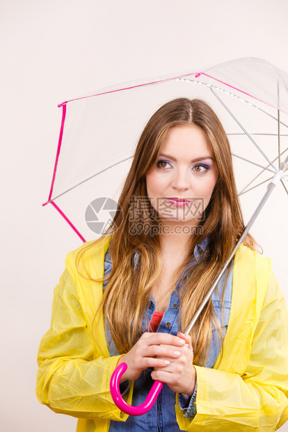 身着防水的黄大衣有透明伞式保护的女时装雨衣少气象学预报和天气季节概念身着防水大衣的妇女则身着雨伞式保护图片