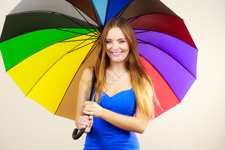 穿着蓝色裙子的女孩站在彩虹伞下灰色的彩虹伞下站立正面微笑的女模型预测和天气季节概念图片