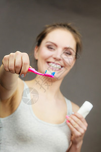 怀着刷牙和膏洗的女人带着刷笑的女孩快乐口腔卫生工作室拍了黑背景女人刷牙图片