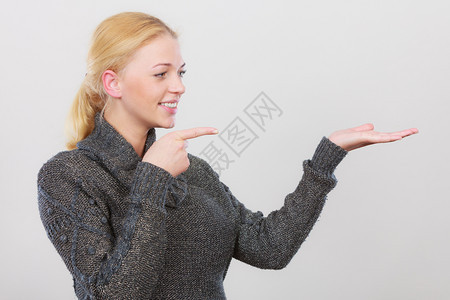 手势指针概念快乐的女士用两只手指在她旁边的右侧工作室用浅灰色背景拍摄快乐的女士用两只手指在右侧图片