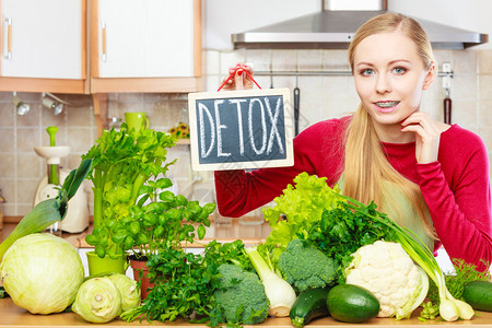 厨房的年轻女有很多绿色蔬菜配有脱毒标志的餐桌图片