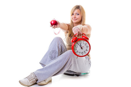 手持苹果测量胶带和大型老式钟表的妇女坐在称重机上图片