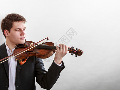 音乐激情爱好概念青年男子穿着优雅的木小提琴演奏工作室拍摄白色背景男子穿着优雅的小提琴演奏图片