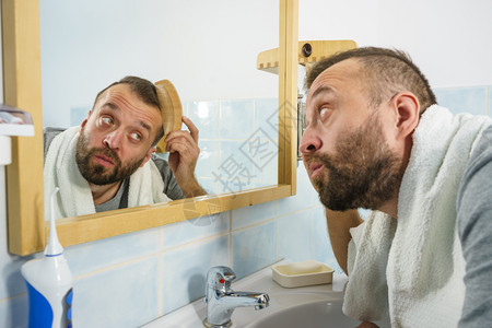 成人男子站在浴室镜前用梳短头发图片