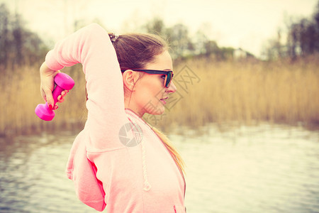 女在户外运动有哑铃举起重量的体外运动健身女孩穿运动服在外面新鲜空气中运动女在户外与哑铃一起运动图片