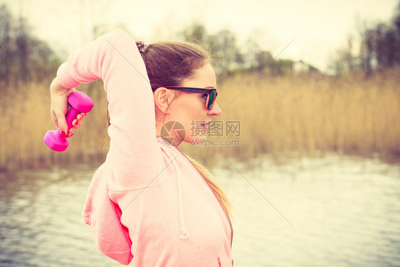 女在户外运动有哑铃举起重量的体外运动健身女孩穿运动服在外面新鲜空气中运动女在户外与哑铃一起运动图片