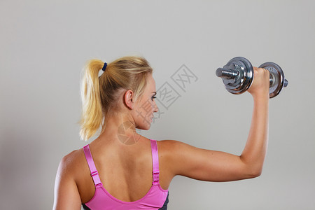 健壮的女举起哑铃重量合适的女孩在锻炼肌肉健身和美后视合适的女举起哑铃重量图片