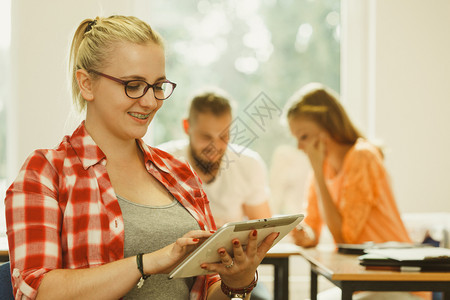 教育高中数字在线学习概念拥有平板电脑的学生女孩在课堂上同班学面前坐在生图片