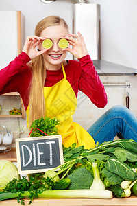 厨房的年轻女有很多绿色蔬菜在餐桌上配有饮食标志厨房的女有绿色食物蔬菜图片