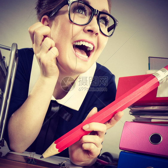 快乐的女商人坐在办公桌工作满文件的夹子图片