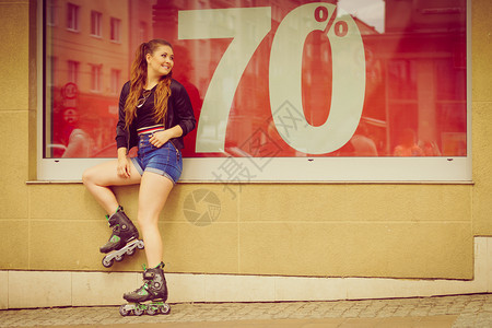 暑假穿溜冰滑的少女在窗口上展示销售标志图片