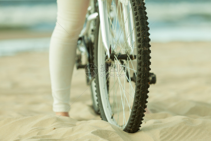 在沙滩上骑自行车的女人图片