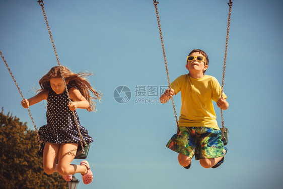 女孩和男孩在幼儿园操场户外玩耍在秋千上玩得很开心图片
