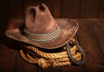 古老的马蹄铁就在经典牛仔帽和黑色木头背景的拉索旁边高清图片