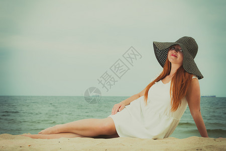 穿着大黑太阳帽的红发女人穿着太阳帽子的红发女人躺在沙滩上图片