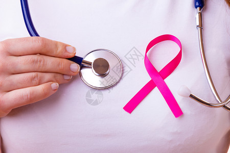 妇女为健康而斗争乳腺癌肿瘤概念粉色丝带和蓝听诊器在女胸前闭合粉色丝带和听诊器在女胸前图片