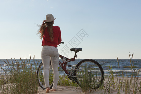 在海边骑自行车的年轻女子背影图片