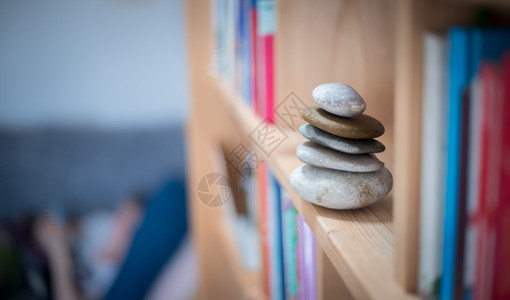风水在书架上家里的石礁在前景和背上模糊的书本平衡与放松图片
