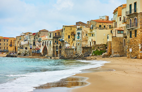 意大利西里CefaluLandmark和海滨度假胜地边的Sandy海滩和旧房子图片