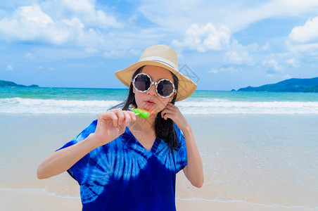 在泰国普吉中午的海洋或自然外度假期间在海滩吃西瓜冰淇淋的亚洲快乐妇女图片