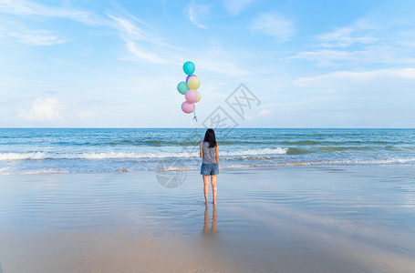 亚洲女在泰国普吉中午的海洋携带多彩气球图片