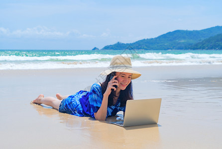 在泰国普吉中午的海洋或自然旅行度假室外时在海滩使用电脑笔记本的亚洲快乐妇女图片