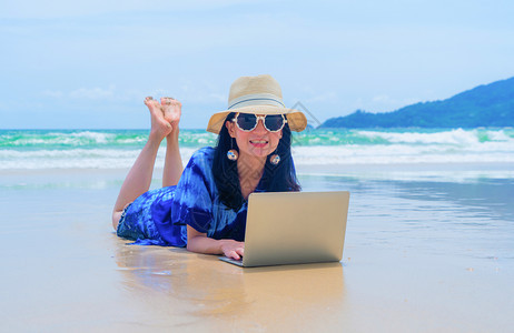 在泰国普吉中午的海洋或自然旅行度假室外时在海滩使用电脑笔记本的亚洲快乐妇女图片