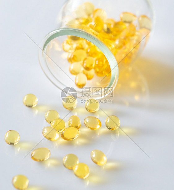 Omega3鱼油舱从玻璃罐中喷出放在白色底的玻璃罐中图片