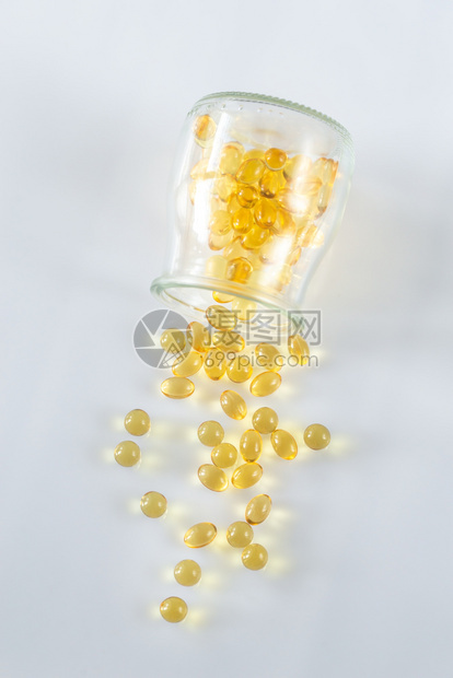 Omega3鱼油舱从玻璃罐中喷出放在白色底的玻璃罐中图片