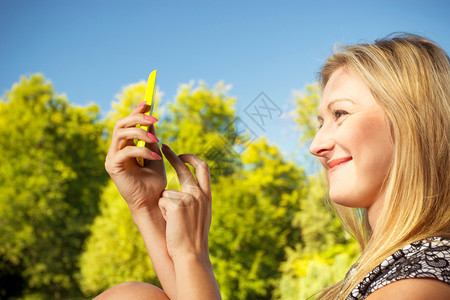 妇女坐在公园休息使用手机拍摄自然照片在外闲暇时间图片