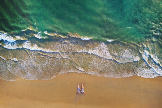 亚洲夫妇躺在海滩上的空中景象海浪滚到岸边旅行度假室外背景安达曼海泰国普吉湾岛夏季的安达曼海泰国普吉湾岛图片