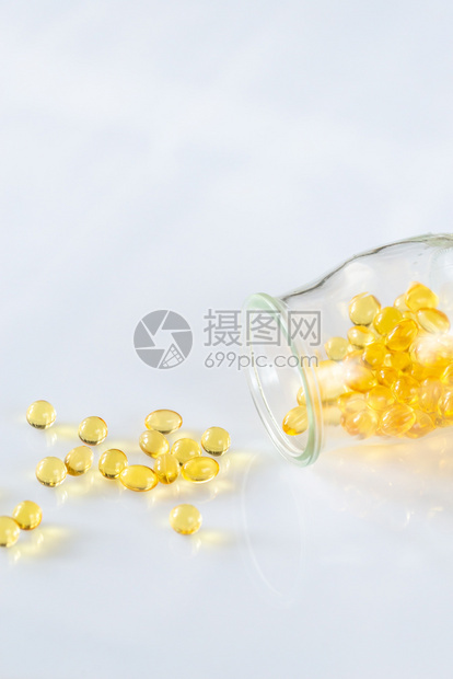 Omega3鱼油舱从玻璃罐中喷出放在白色底的玻璃罐中图片