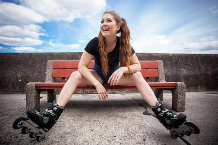 快乐的年轻女子穿着滑冰鞋在长途旅行后放松快乐的年轻女子穿着滚冰鞋背景图片