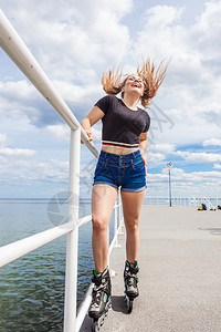 快乐的年轻女子在海上穿滑冰鞋女孩在夏天玩得开心快乐的少女穿滑冰鞋图片