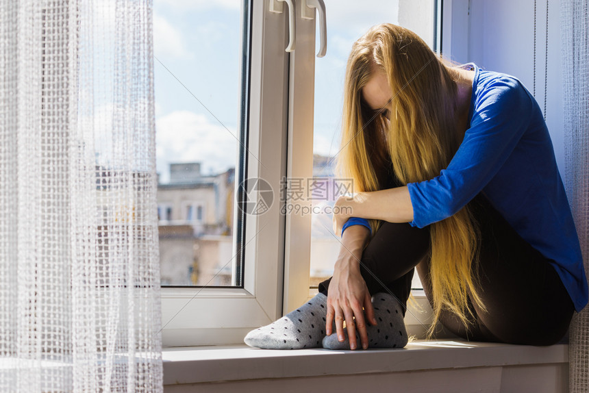 孤单悲伤的年轻女长发少坐在窗边的长发少女坐在深沉的思乡中在城市背景迷失在思乡城市背景坐在窗边的悲伤沮丧少女坐在窗边的悲伤和沮丧少图片