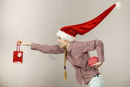 穿着风吹的圣诞老人帮手帽子书包和假大脑的快乐妇女图片