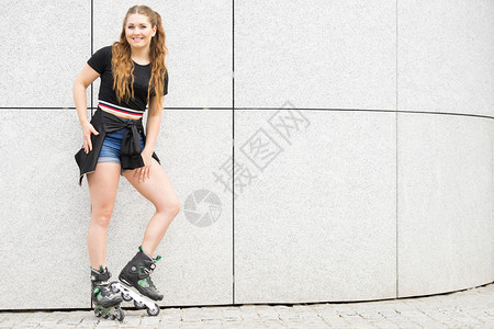 快乐的年轻女子穿着滑雪冰在城里骑马图片