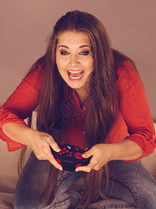 坐在沙发上玩游戏的神经怪胎年轻成女子在视频控制台玩耍游戏者概念玩游戏的年轻女子图片