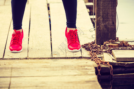 部分培训在户外积极运动的女孩在湖岸木码头上穿红鞋的双腿在木码头上穿红运动鞋的双腿图片
