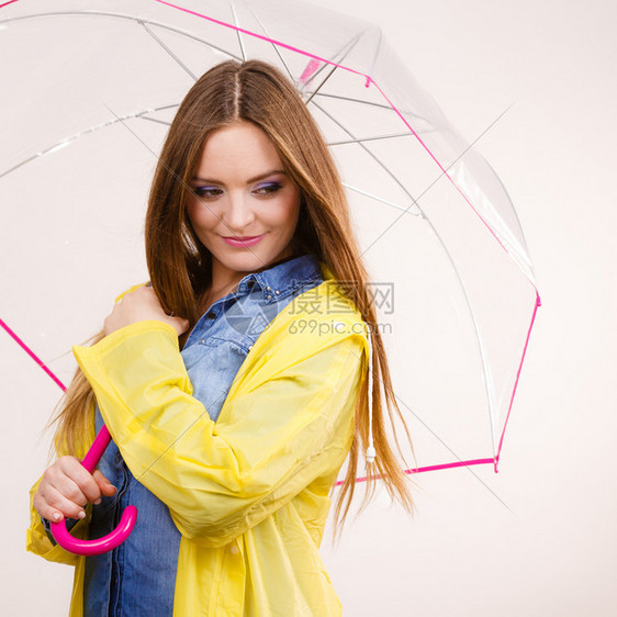 身着防水黄色大衣站在雨伞下玩得开心的雨中微笑女孩气象预报和天季节概念身着雨伞下防水大衣的妇女图片