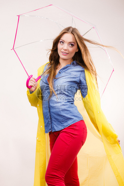 身着防水黄色大衣站在雨伞下玩得开心的雨中微笑女孩气象预报和天季节概念身着雨伞下防水大衣的妇女图片