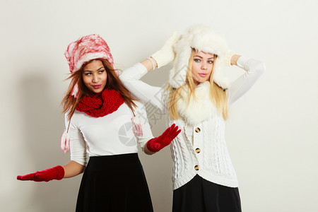 冬季时装时装冬人概念两个穿冬装的女孩着毛帽的迷人女背景