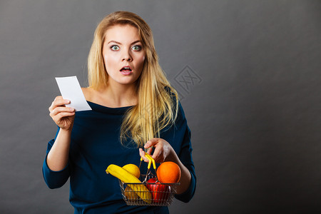 拿着水果的购物篮惊吓妇女看着账单收据害怕巨额价格图片
