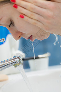 在浴室用清洁水洗脸的妇女照顾外衣的孩早间卫生皮肤治疗浴室洗脸的妇女卫生图片