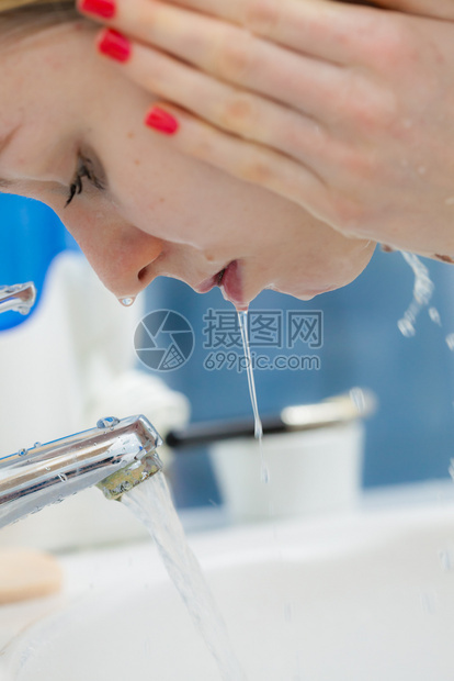 在浴室用清洁水洗脸的妇女照顾外衣的孩早间卫生皮肤治疗浴室洗脸的妇女卫生图片