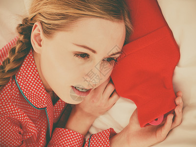 睡在床上的妇女用温暖红热水瓶睡觉发烧流感处理物体概念睡在温暖的红热水瓶上妇女图片