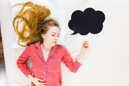 穿着可爱的粉红色睡衣黑思维或言语泡睡在床上的年轻女穿着睡衣躺在床上的年轻女穿着睡衣图片