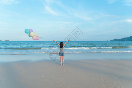 快乐的亚洲女在泰国普吉中午的海洋或自然度假室外旅行中在海滩上携带多彩气球图片