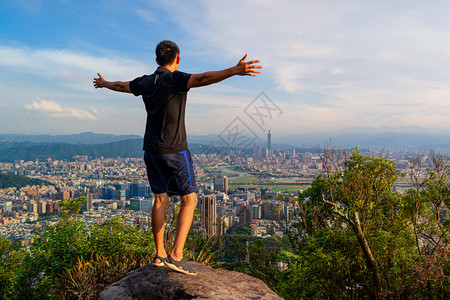一位亚洲旅游者在台北市山丘陵的岩石上徒步旅行并享受观光景色在旅游行度假或节日期间在冒险概念下的北山丘上在旅游度假或节日中天桥和高图片
