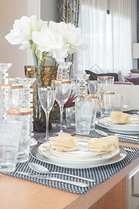餐桌中央有金色玻璃和白花图片